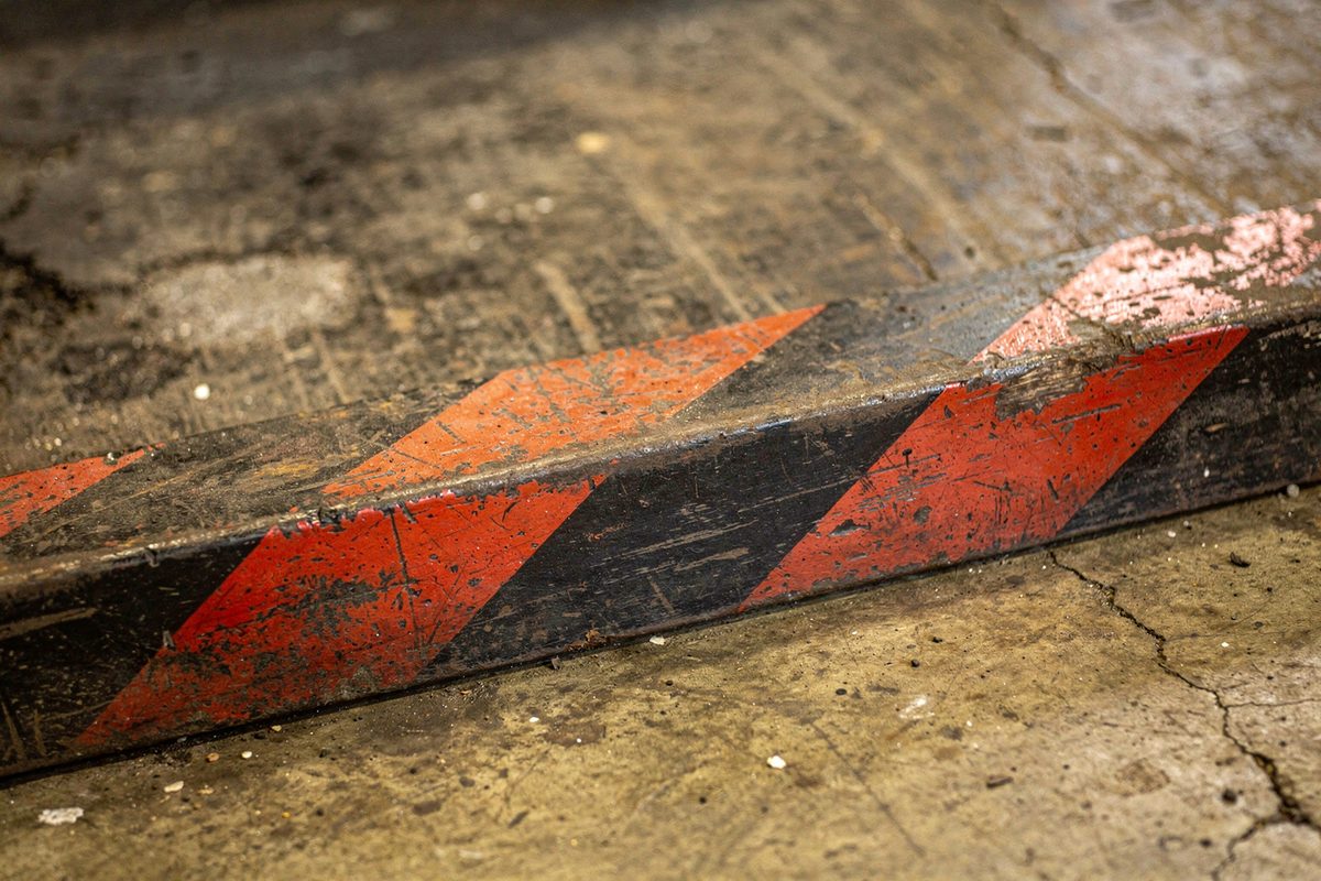 A worn diagonal red and black hazard stripe painted along a workbench base